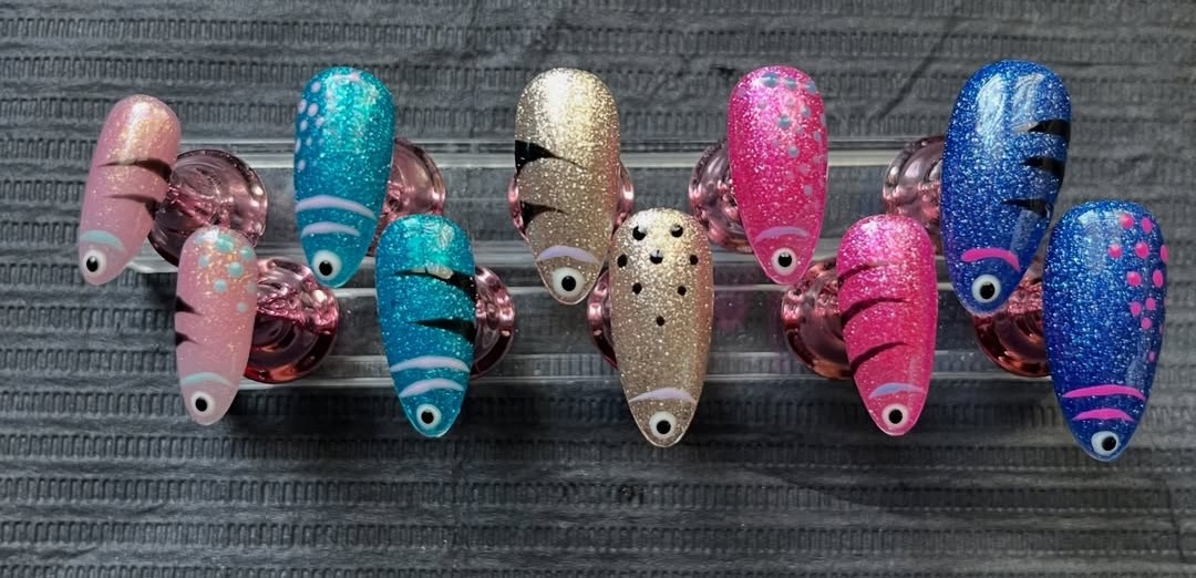 Fish Lure Set — hyper-realistic fishing-lure press-on nails in iridescent pink, teal, gold and blue glitter with painted eyes